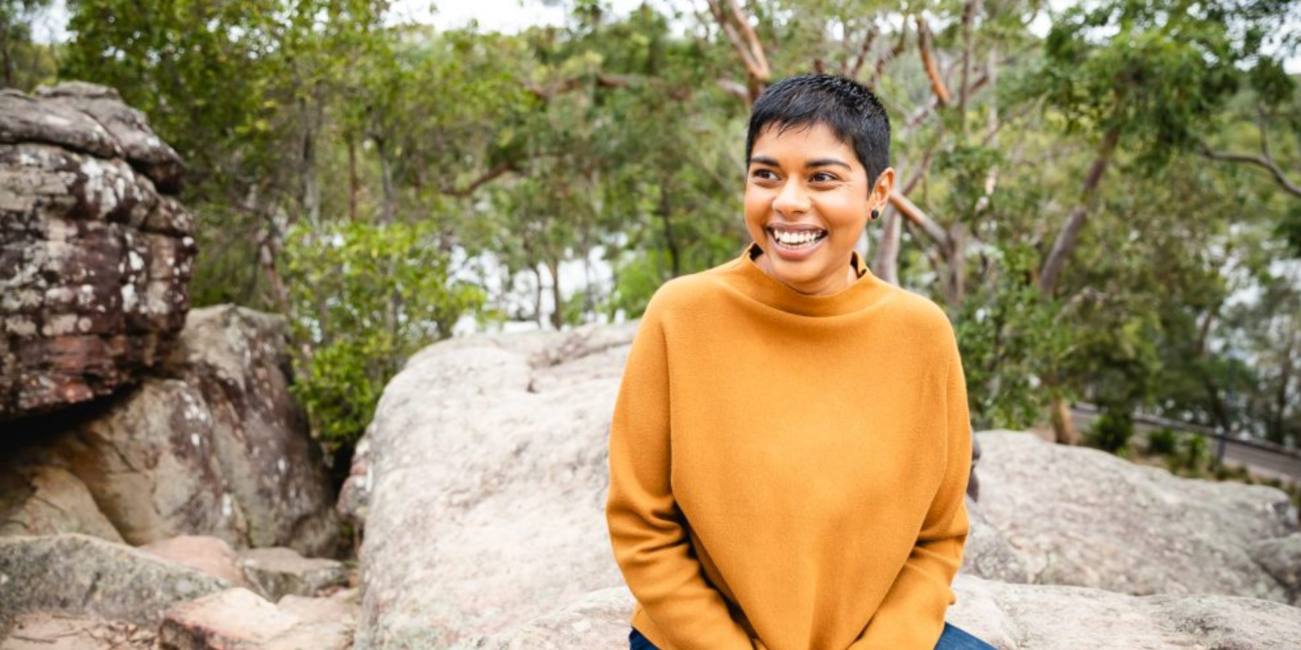 Author Dinuka McKenzie sitting in the bush smiling